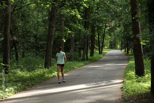 The girl is engaged in sports walking on the path in the city park