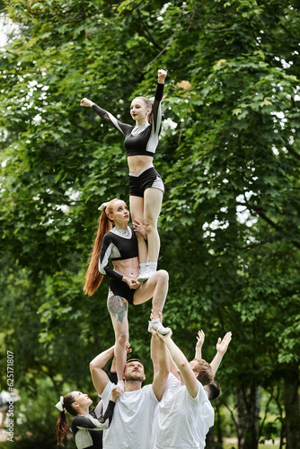 Vertical image of cheerleading girls doing tricks at performance outdoors