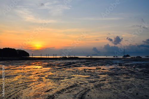 Beautiful sunrise scene over sea pier with sky reflection in water during low tide in Krabi, Thailand