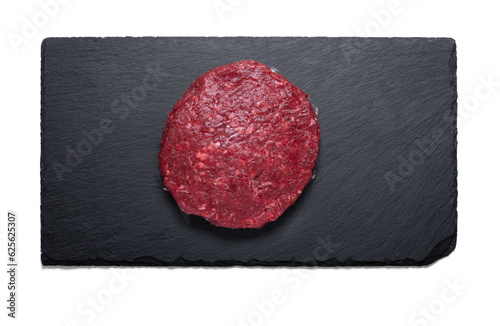 Raw beef maxi burger on a slate plate from above with a semitransparent shadow