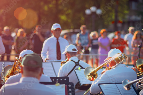 Jazz band performance on an open city stage on a summer evening. A group of wind instrument musicians in the sun. Selective focus.