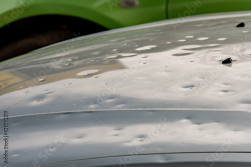 Car hood damaged by major hailstorm hailstones. Car insurance repair dents. Dented car bonnet