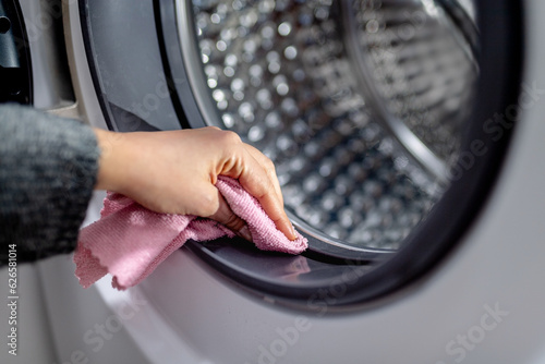 hand cleaning washing machine from dirt and mold with pink cloth. Wiping rubber seal on washing machine drum