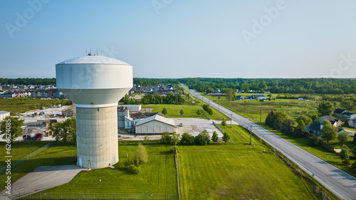 Rural area aerial nondescript white water tower with nearby housing