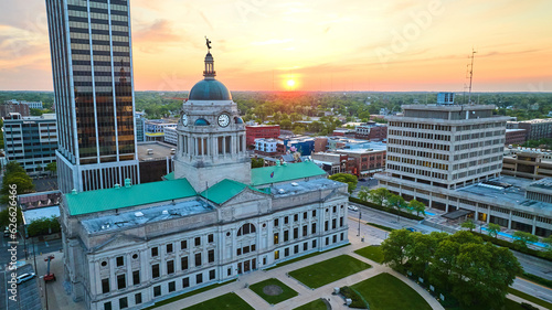 Sunrise on horizon in golden aerial of close up of downtown Fort Wayne courthouse
