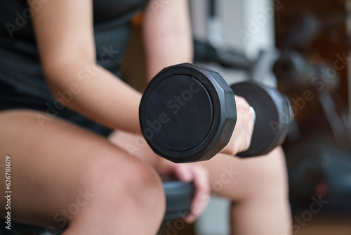 Cropped image of female hands lifting dumbbells at gym. Fitness, workout, gym exercise and healthy lifestyle concept.