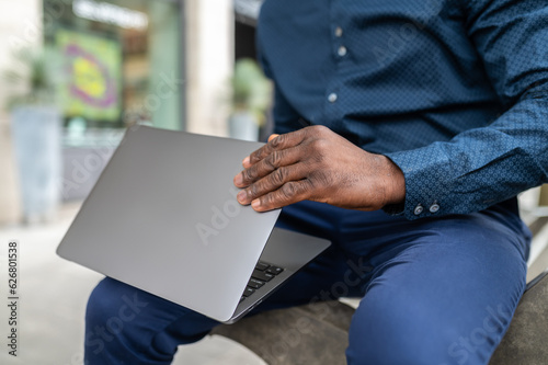 Dark-skinned man with a laptop working outside