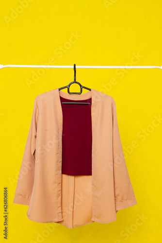 Orange outwear women for daily wear or formal outfit. With White Tanktop in. Outwear on the hanger on the yellow background. Able to add some text or another object