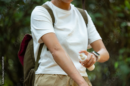 Woman spraying insect repellent at her hand