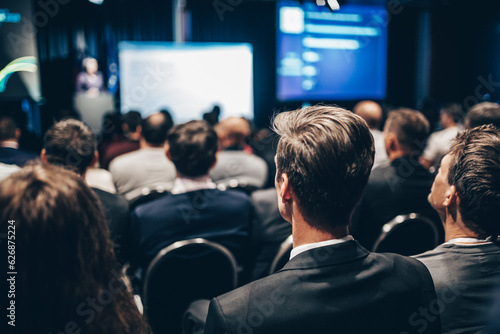 Speaker giving a talk in conference hall at business event. Rear view of unrecognizable people in audience at the conference hall. Business and entrepreneurship concept