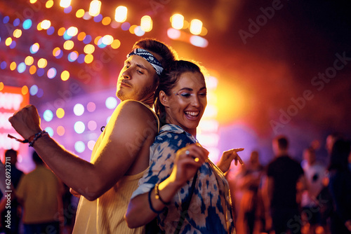 Happy woman and her boyfriend dancing at open air music concert at night.