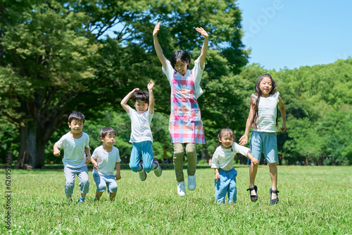 緑地でジャンプする子供たちと女性