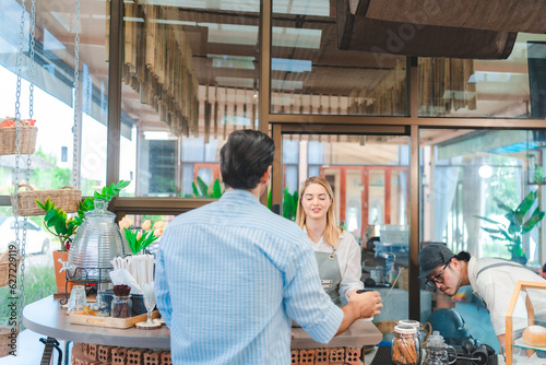 Smiling waitress wear apron take order talk to clients serving restaurant guests choosing food drinks menu in cafe coffeehouse bar, waiting staff, good customer service, cashier serving customers