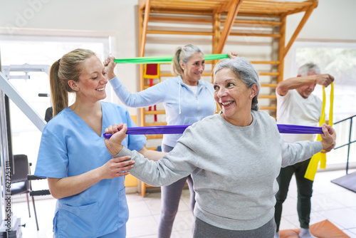 Therapist assisting senior woman doing workout at rehabilitation center