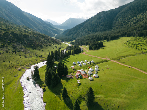 Top view of yurts nomad village in Jety-Oguz gorge in Kyrgyzstan. Karakol national park. Traditional nomad's yurts on beautiful mountain meadows in the green mountains in Karakol area in the summer. 