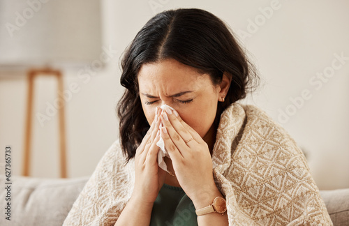 Nose, tissue and sick woman sneezing on a sofa with allergy, cold or flu in her home. Hay fever, allergy and female with viral infection, problem or health crisis in a living room with congestion