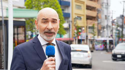 A Caucasian male reporter broadcasting on television in a local city.