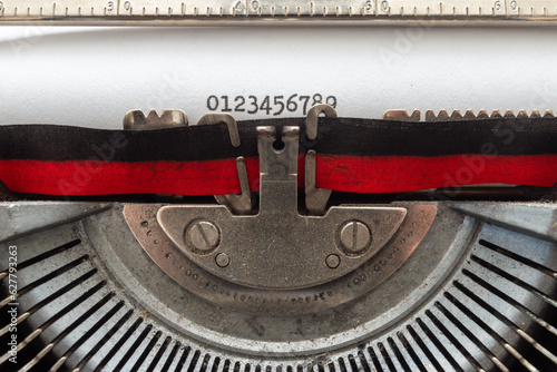 typing with an old typewriter. The numbers from 0 to 9 and the lowercase alphabet, written on a white sheet of paper, with a two-tone, black and red ribbon, and the rest of the steel mechanisms