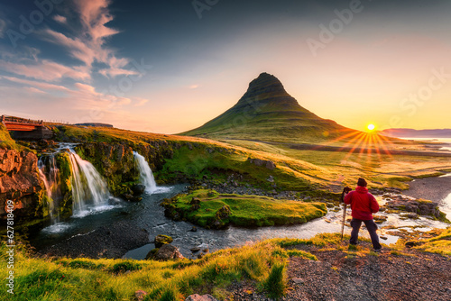 Sunrise over volcanic Kirkjufell mountain and photographer man standing in summer at Icelandnaefellsnes peninsula, Iceland
