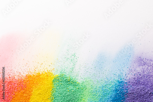 Close up of stripes of rainbow coloured sand and copy space on white background