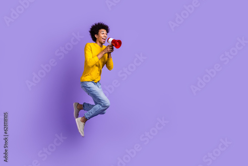 Full length size view photo of funny crazy man jumping with megaphone loudspeaker proclaim announce isolated on violet color background