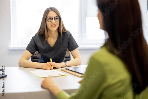 Portrait of a young doctor during a consultation with a patient in the office. Woman at an appointment with a dermatologist