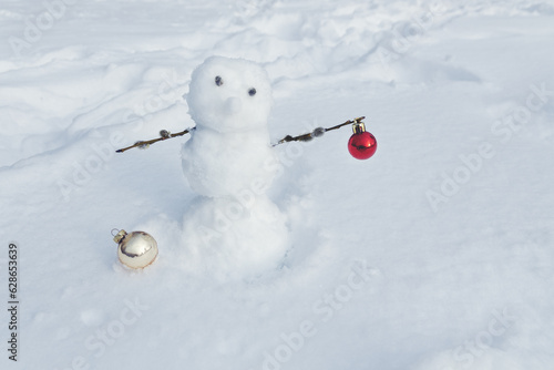 spring snowman with willow branches and Christmas tree decorative balls on snow