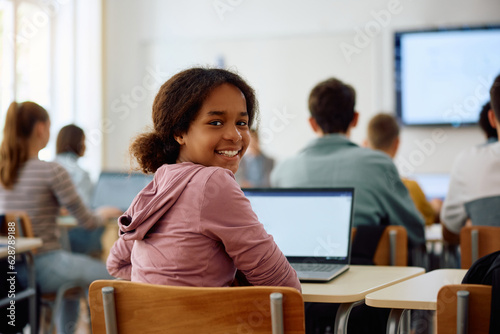 Happy black female student during computer class at high school looking at camera.
