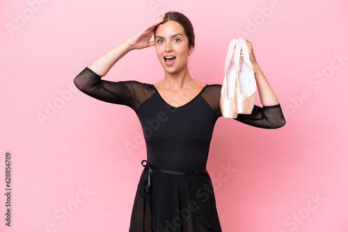 Young caucasian dance woman doing ballet isolated on pink background with surprise expression