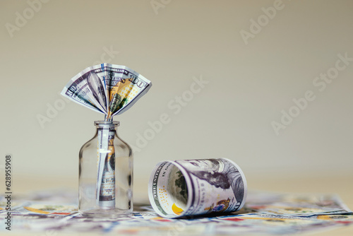 billete de 100 dolares dentro de un frasco de vidrio, sobre mas dolares en la meza, concpeto de ahorros y finanzas
