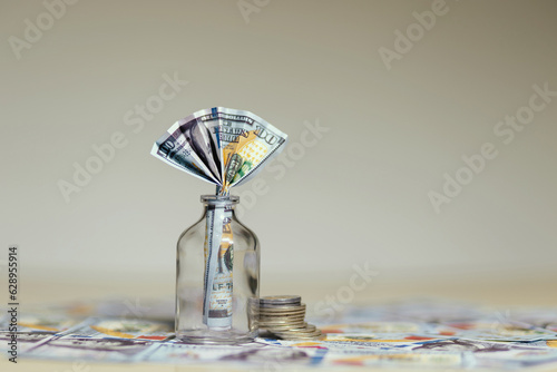 billete de 100 dolares dentro de un frasco de vidrio, sobre mas dolares en la meza, concpeto de ahorros y finanzas