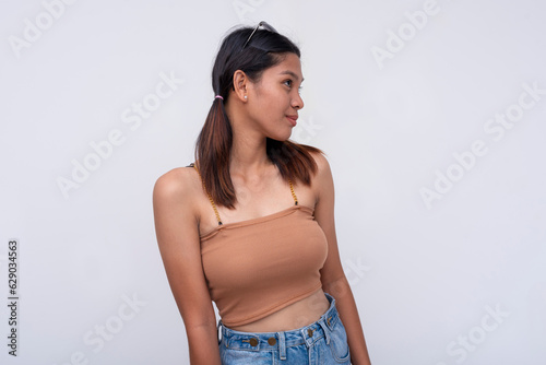A young woman looks away feigning that she is only mildly interested while actually smiling. Playing hard to get. Isolated on a white background.