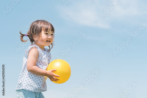 夏休みに青空の下でボール遊びをするアジア人の子供（女の子） 