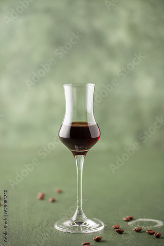 Coffee liqueur in stylish grappa glass and coffee beans on the table