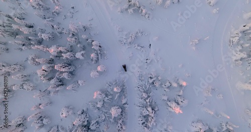 Aerial view above a snowmobile driving uphill a snowy fell, winter dusk in Lapland