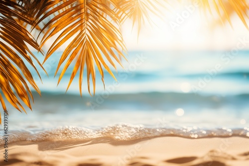 Beautiful background for summer vacation and travel. The golden sand of the tropical beach, blurry palm leaves, and bokeh highlights on the water