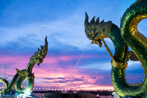 Big green naga statue in riverside on mekong river is landmark in nongkhai city Thailand with twilight background.