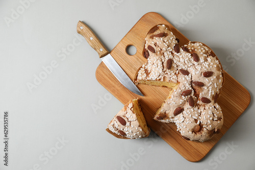 Delicious Italian Easter dove cake (traditional Colomba di Pasqua) and knife on light table, top view. Space for text