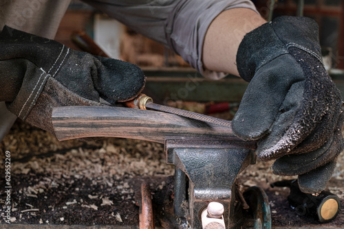 Hand craftsman uses rasp decorate to polish the handle wood hammer handle