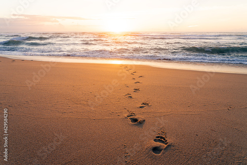 Footprints on the sand of a beach at sunset