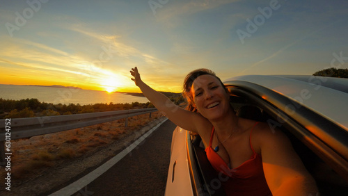 PORTRAIT, LENS FLARE: Happy lady smiles through window of a car driving by sea