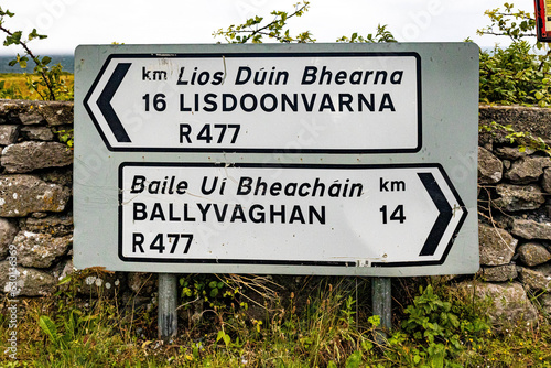 Traditional Irish road sign to Lisdoonvarna and Ballyvaghan towns written in English and Gaelic