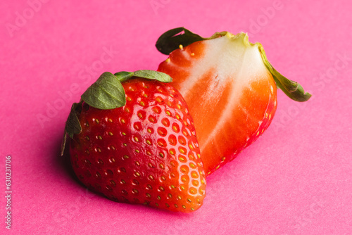 Close up of halved strawberry and copy space on pink background