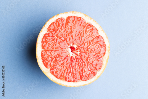 Close up of half of red grapefruit and copy space on blue background