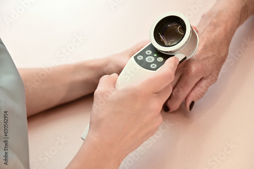Female dermatologist examining hand with dermatoscope for skin diseases and skin cancer