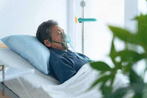 酸素マスクをつけてベッドに寝るシニア男性