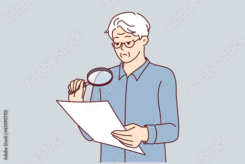 Experienced businessman is checking legal contract using magnifying glass to read fine print. Elderly man holds document and carefully studies all clauses of contract before signing or sealing