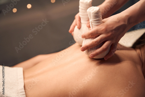 Massotherapist giving upper back hot compress massage to patient