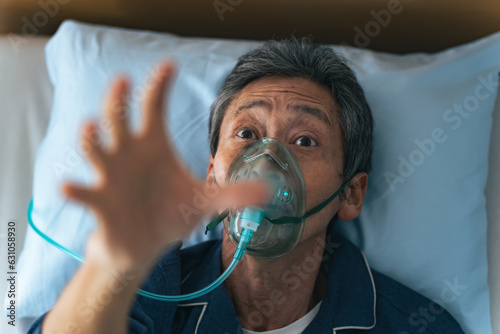 酸素マスクをつけて苦しむシニア男性