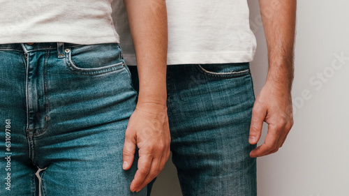 Heterosexual couple hands. Mid section. Close-up of man and woman hands together. Crop unrecognizable boyfriend and girlfriend in jeans hands while standing, white background